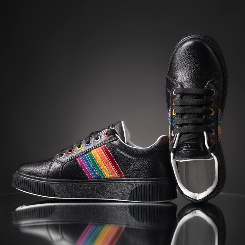 Black leather trainers with coloured stripes on a dark surface, photo by José Martin Segura Benites on Pexels