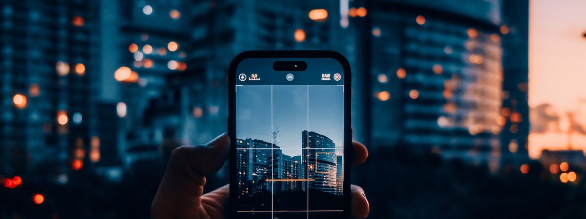 Mano fotografiando rascacielos con el móvil al atardecer