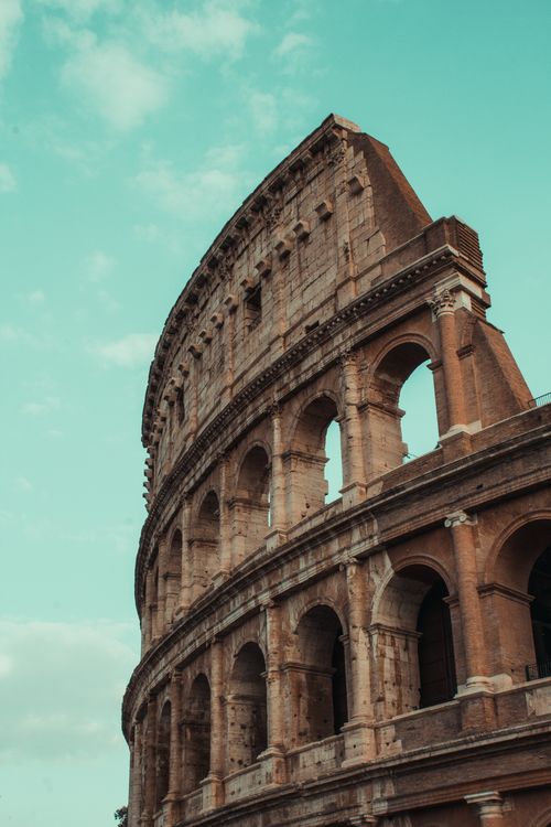 Free Stunning view of the ancient Colosseum in Rome with a vibrant blue sky backdrop. Stock Photo