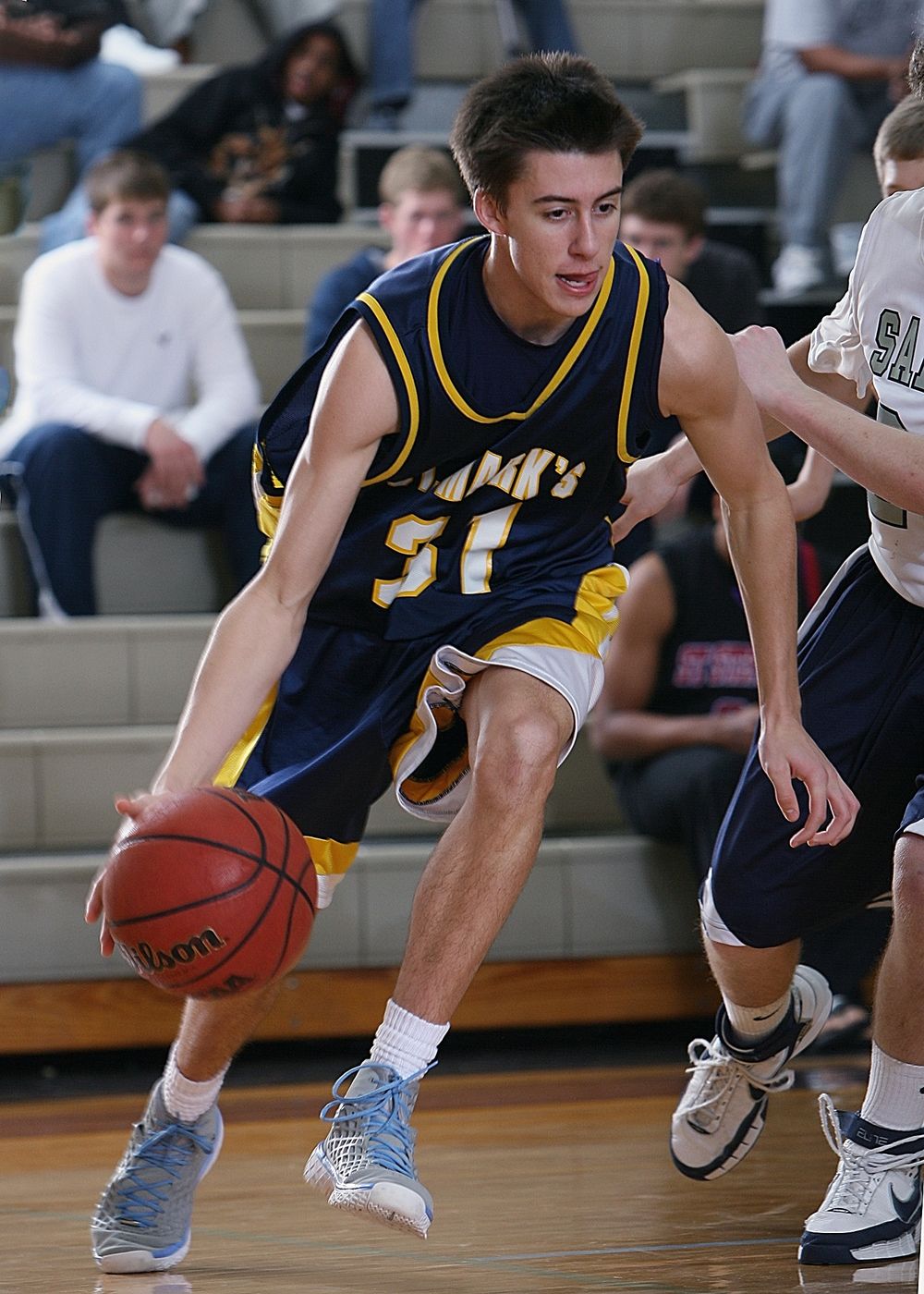 A teen basketball player focused during a game in a school gym