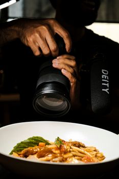 Photographer capturing a dish in a restaurant setup, showcasing food art.