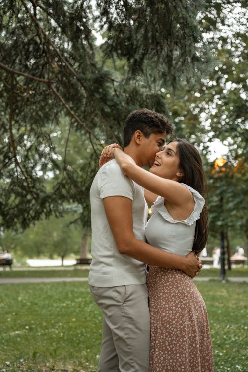 Free A joyful young couple embracing in a serene green park setting. Stock Photo