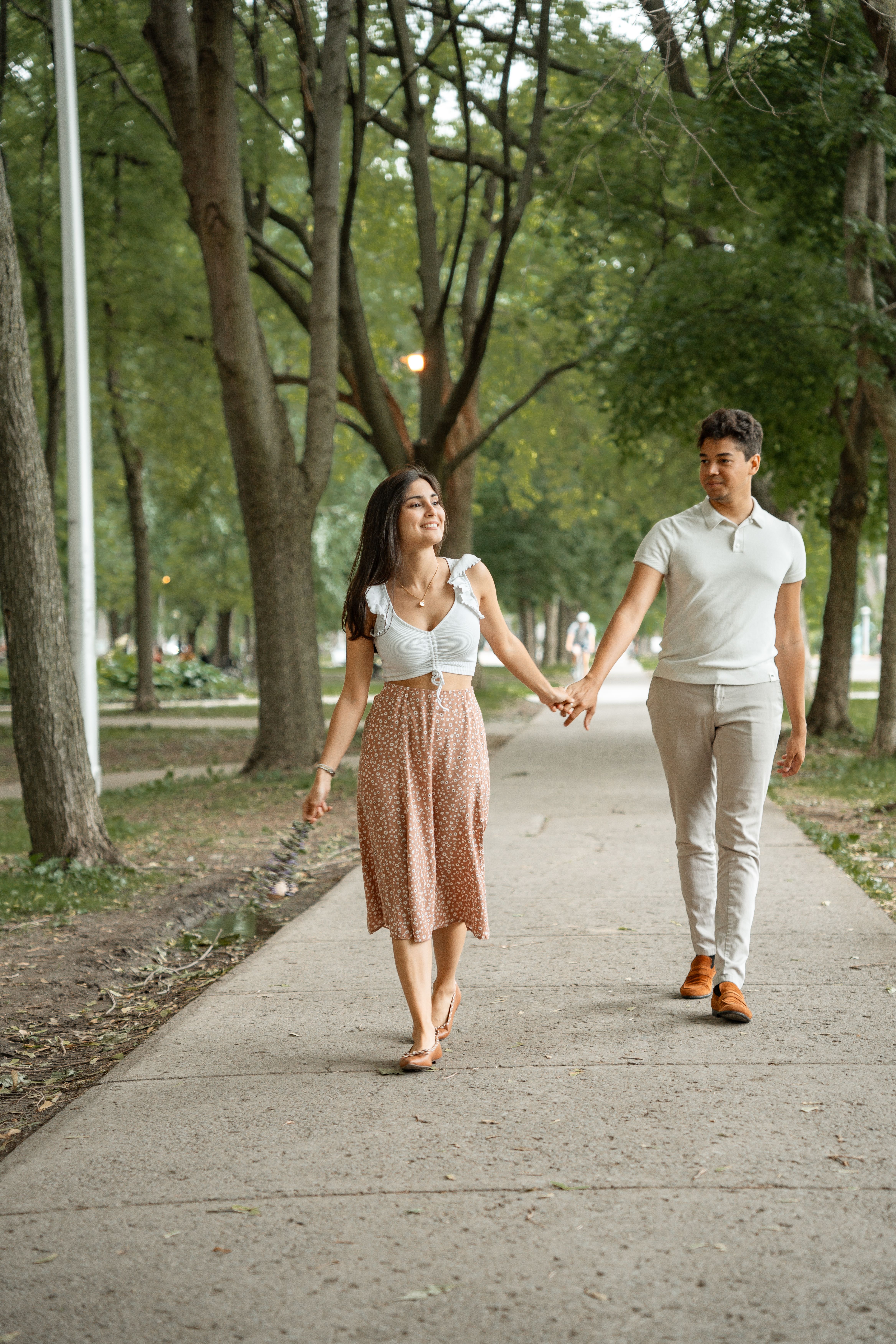 A couple holding hands walking down a sidewalk · Free Stock Photo
