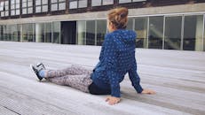 一名少年随意坐在木甲板上，展现出都市的现代感和休闲气息