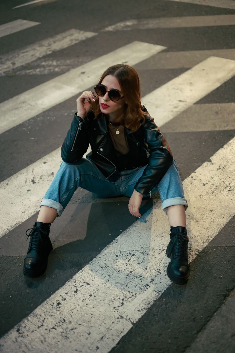 Woman in Black Leather Jacket Sitting on Sidewalk · Free Stock Photo