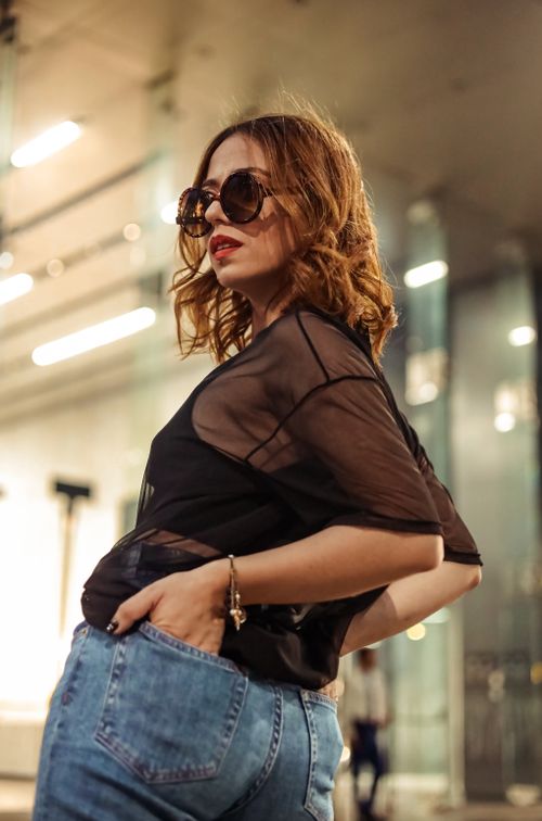 Free Fashionable woman in a black blouse and sunglasses posing in an urban setting, showcasing modern style. Stock Photo