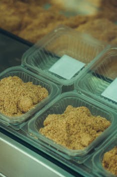 Plastic containers filled with golden-brown packed food, displayed in a store setting for food sales.