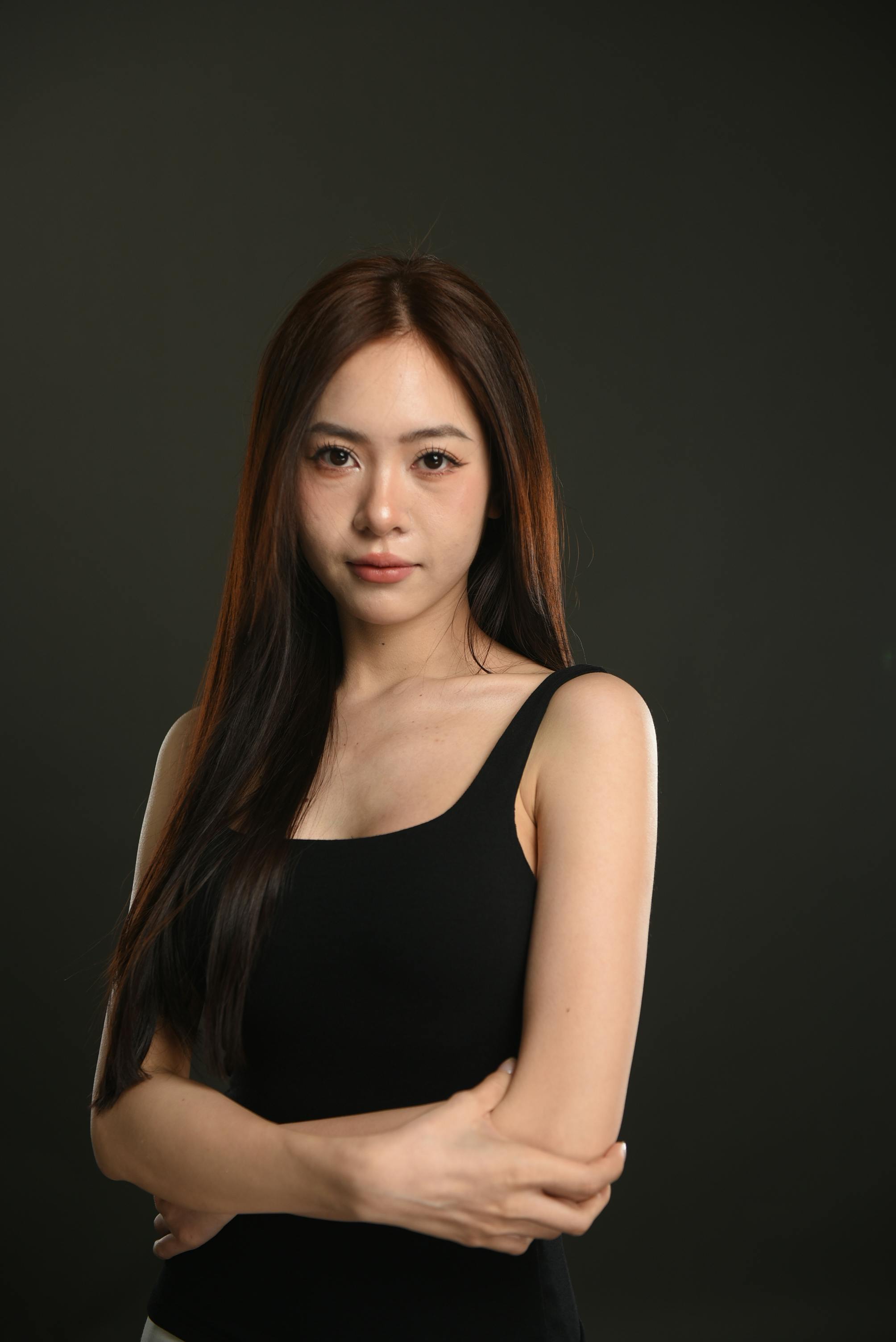 Portrait of a young woman with long black hair wearing a tank top, photographed in a studio setting.