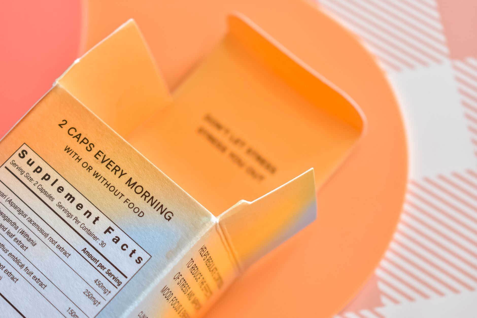 High angle view of an open supplement box on a peach-themed surface
