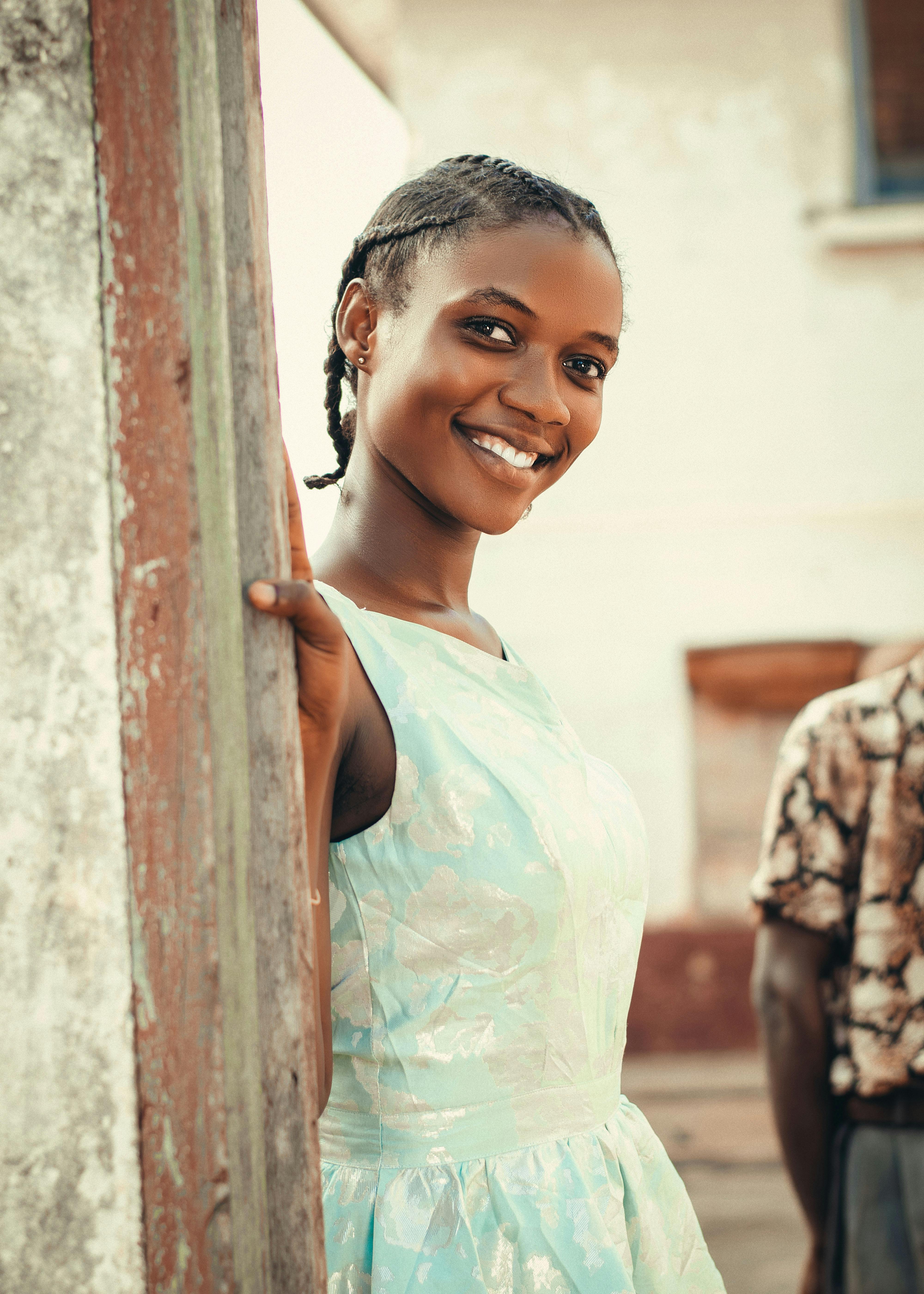 a young woman smiling and leaning against a wall