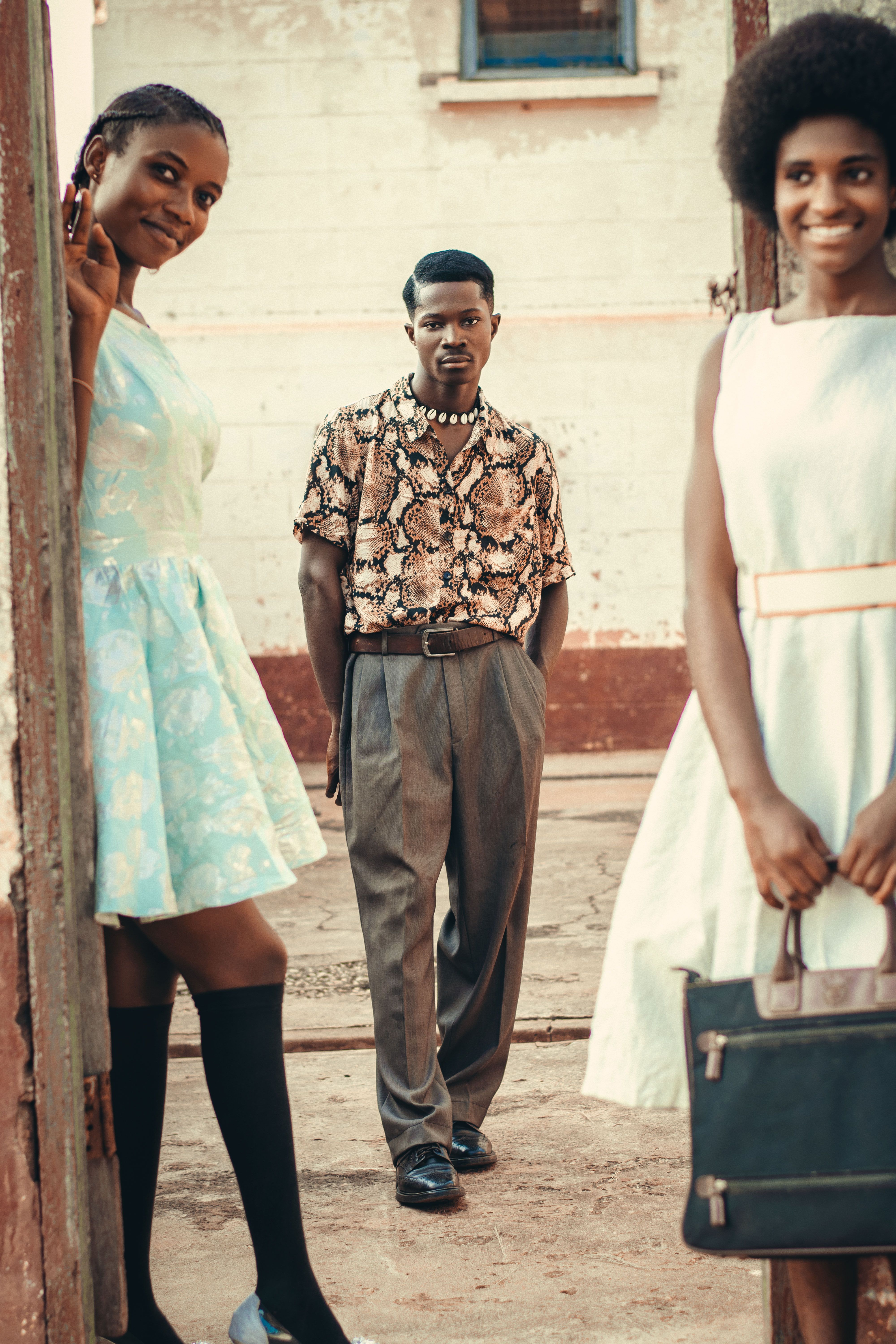 Group of friends in retro fashion posing outdoors, showcasing stylish dresses and shirts.