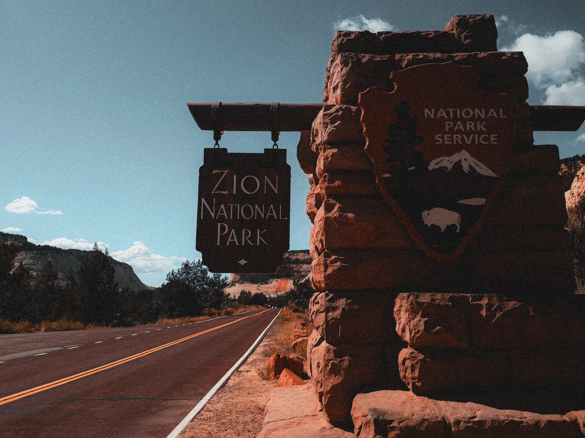 Wooden Yellowstone National Park entrance sign beside the road Wooden Yellowstone National Park entrance sign beside the road
