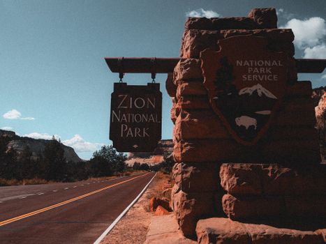 Explore Zion National Park with its iconic entrance sign along a picturesque road in Utah.
