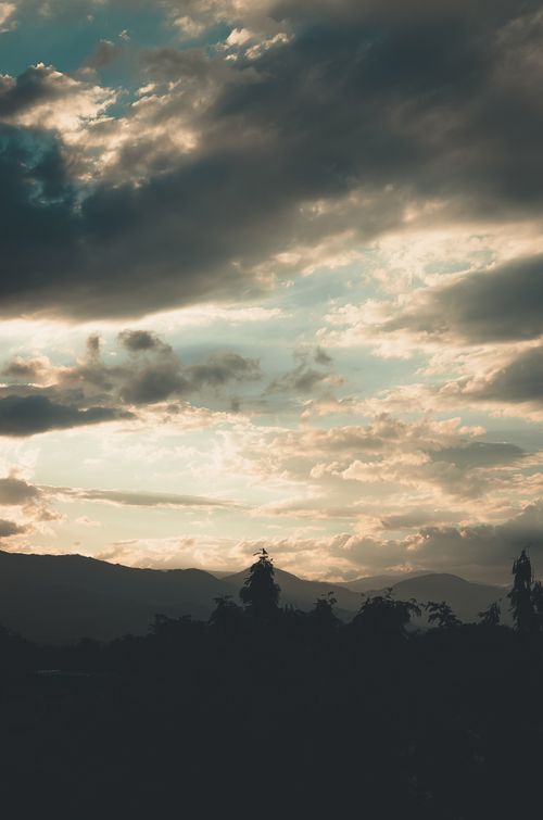 Free Dramatic mountain landscape featuring storm clouds and a stunning sunrise backdrop. Stock Photo