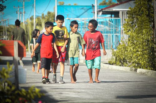 Free Group of children walking barefoot in a sunny village in Agats, Papua, Indonesia. Stock Photo