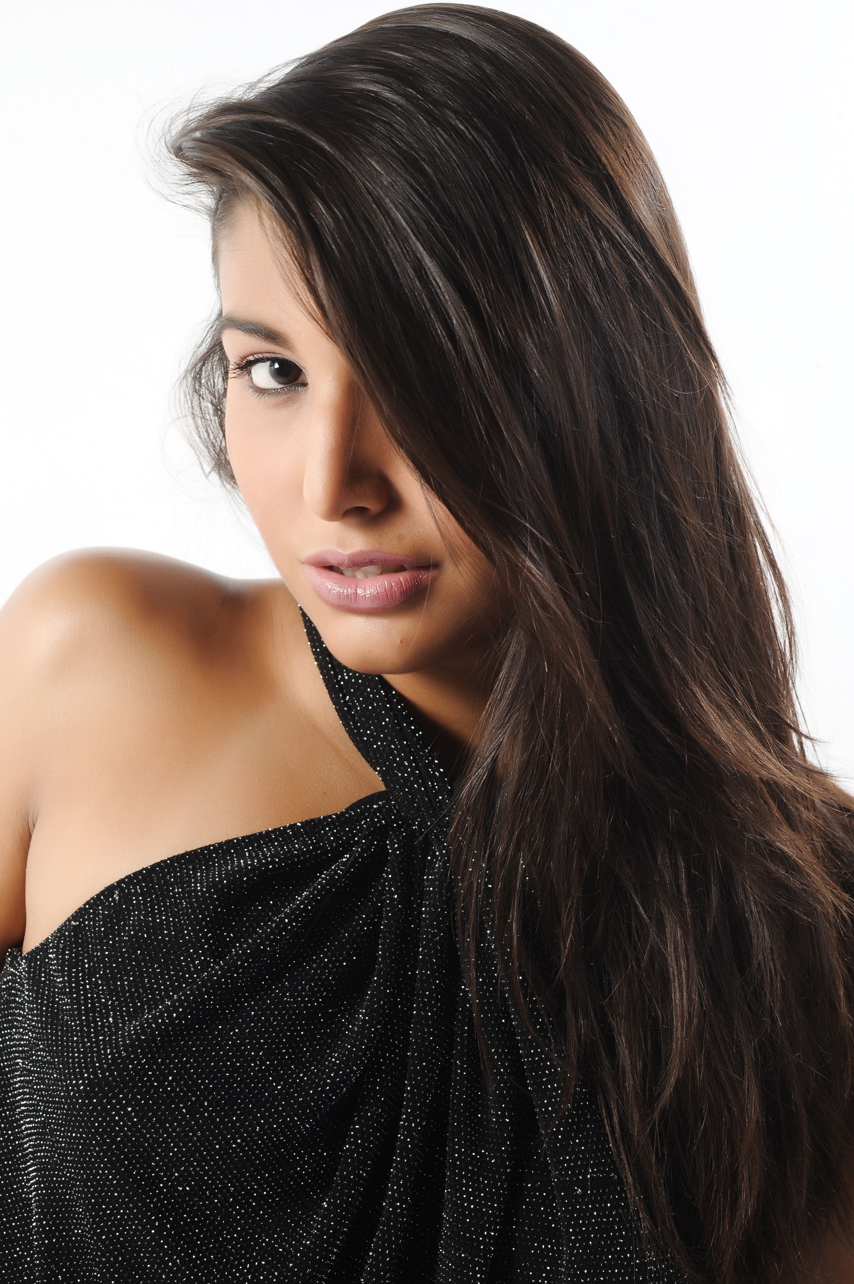 Stunning studio portrait of a young woman in a sparkly black dress on a white background.