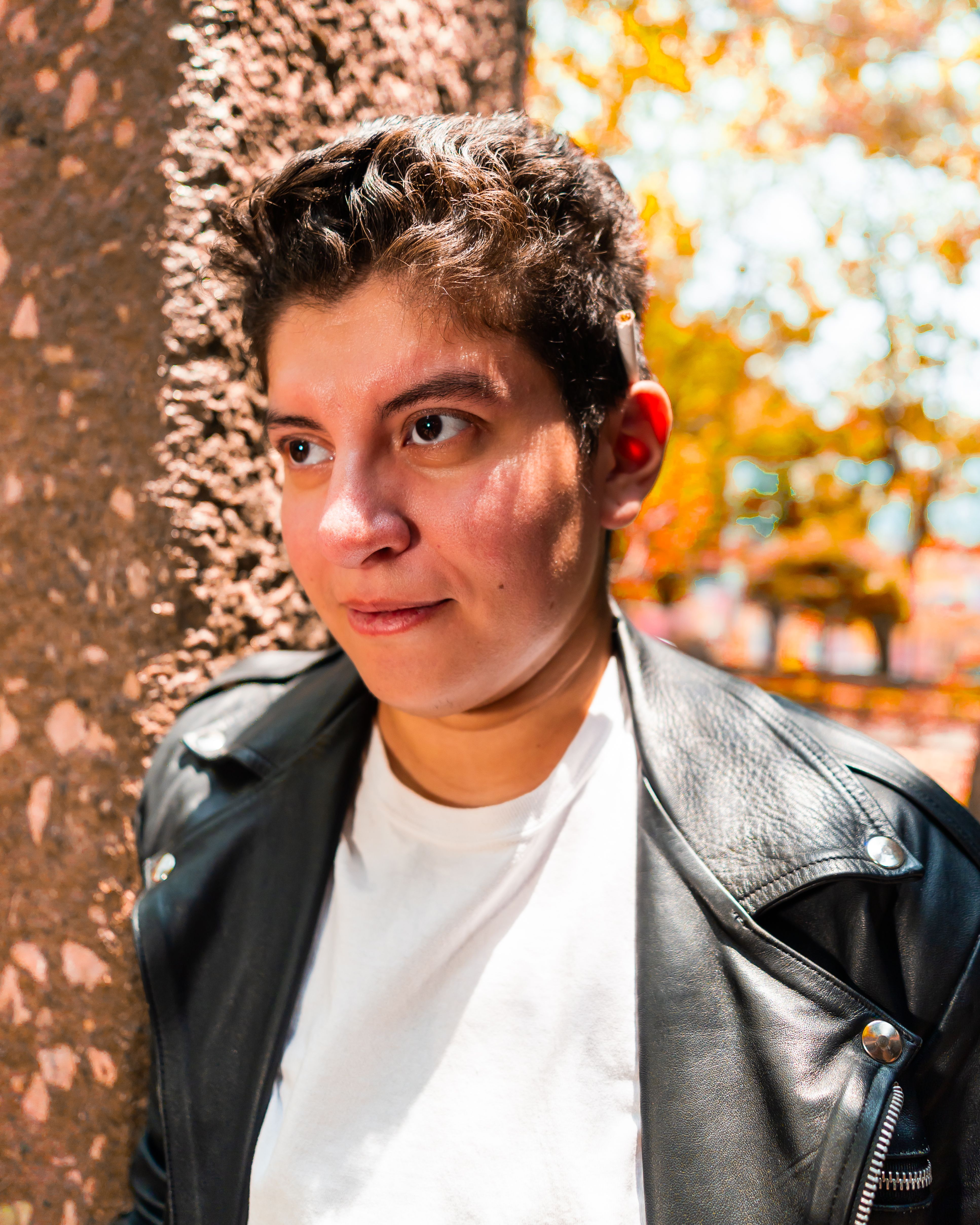 Fotomural Un vibrante retrato al aire libre de una persona joven con chaqueta de cuero contra un fondo texturizado en la temporada de otoño.