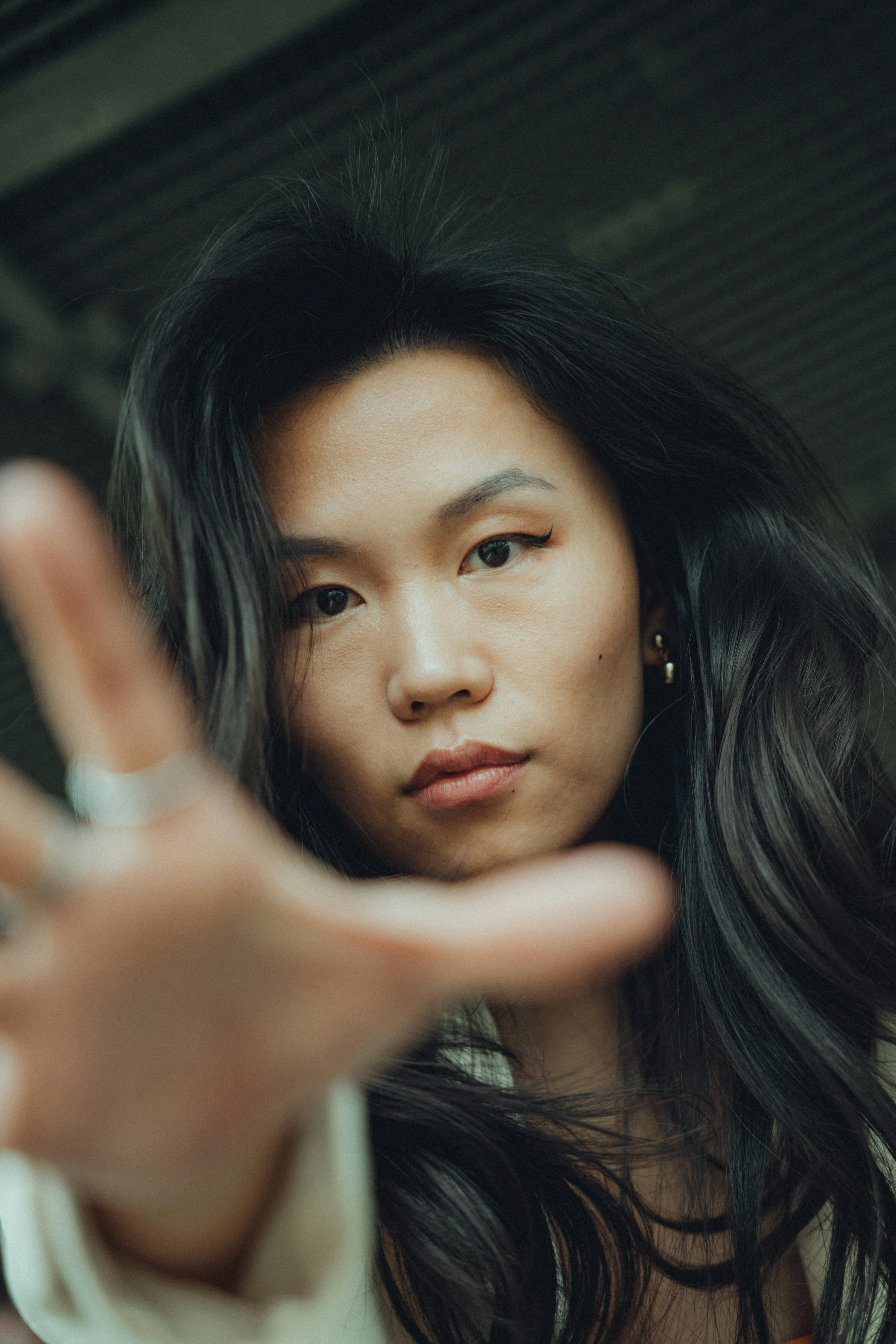 Intimate portrait of a young woman reaching towards the camera with a serious expression.