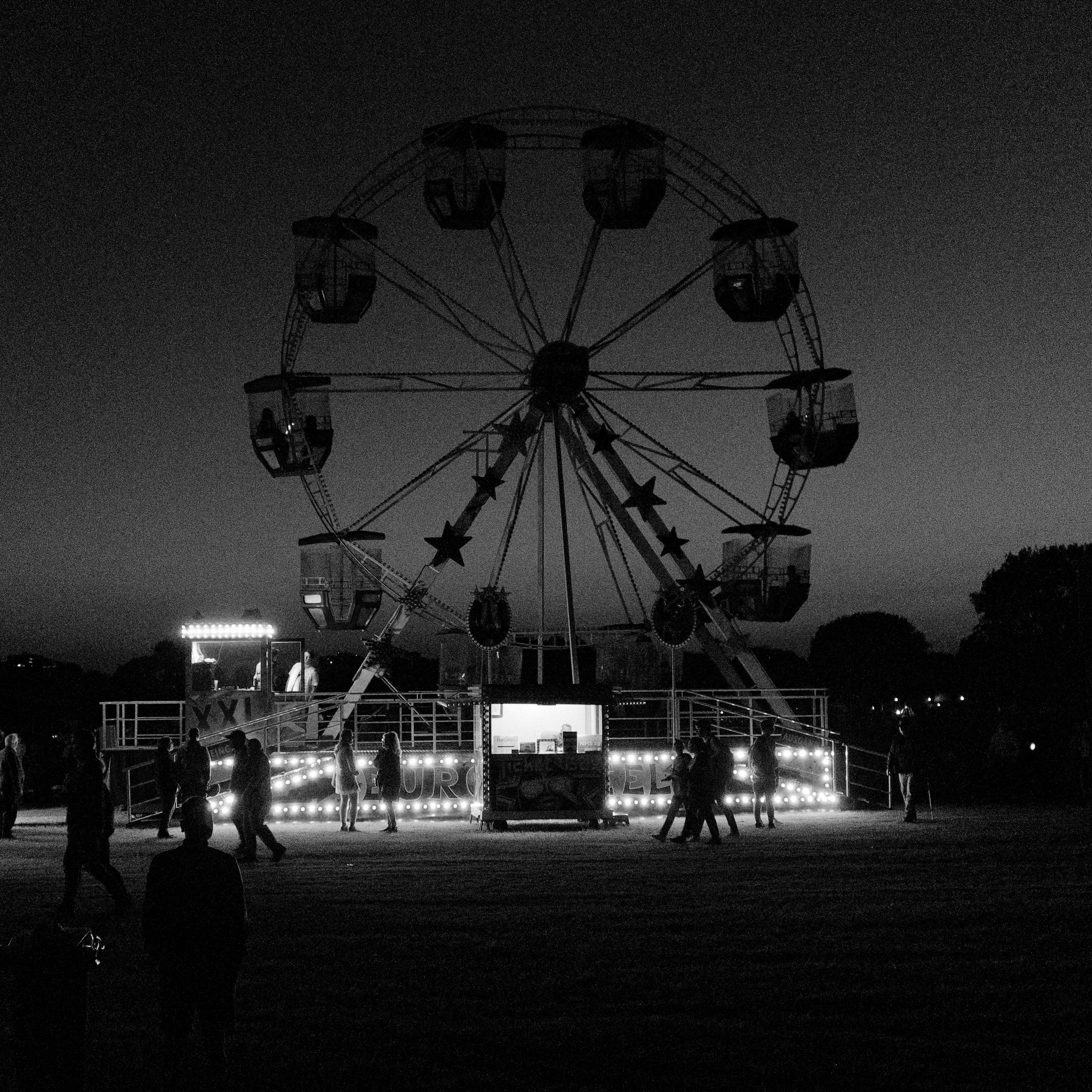 A captivating black and white photo of a Ferris wheel illuminated at night, capturing the essence of amusement.