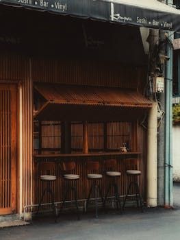 Exterior of an empty urban sushi bar with wooden design and bar stools.