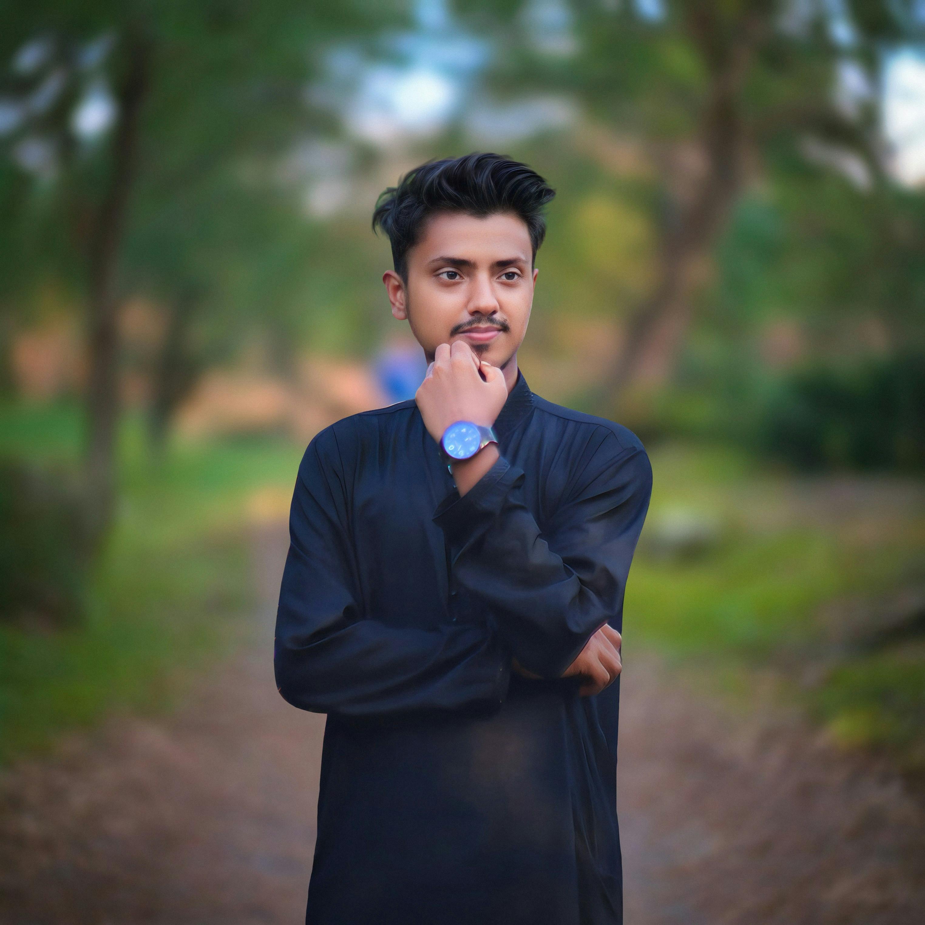 A young man in a black outfit poses confidently in a park in Sylhet, Bangladesh.