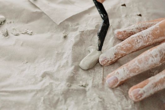 Hands working with clay on a textured surface, showcasing creativity and craftsmanship.