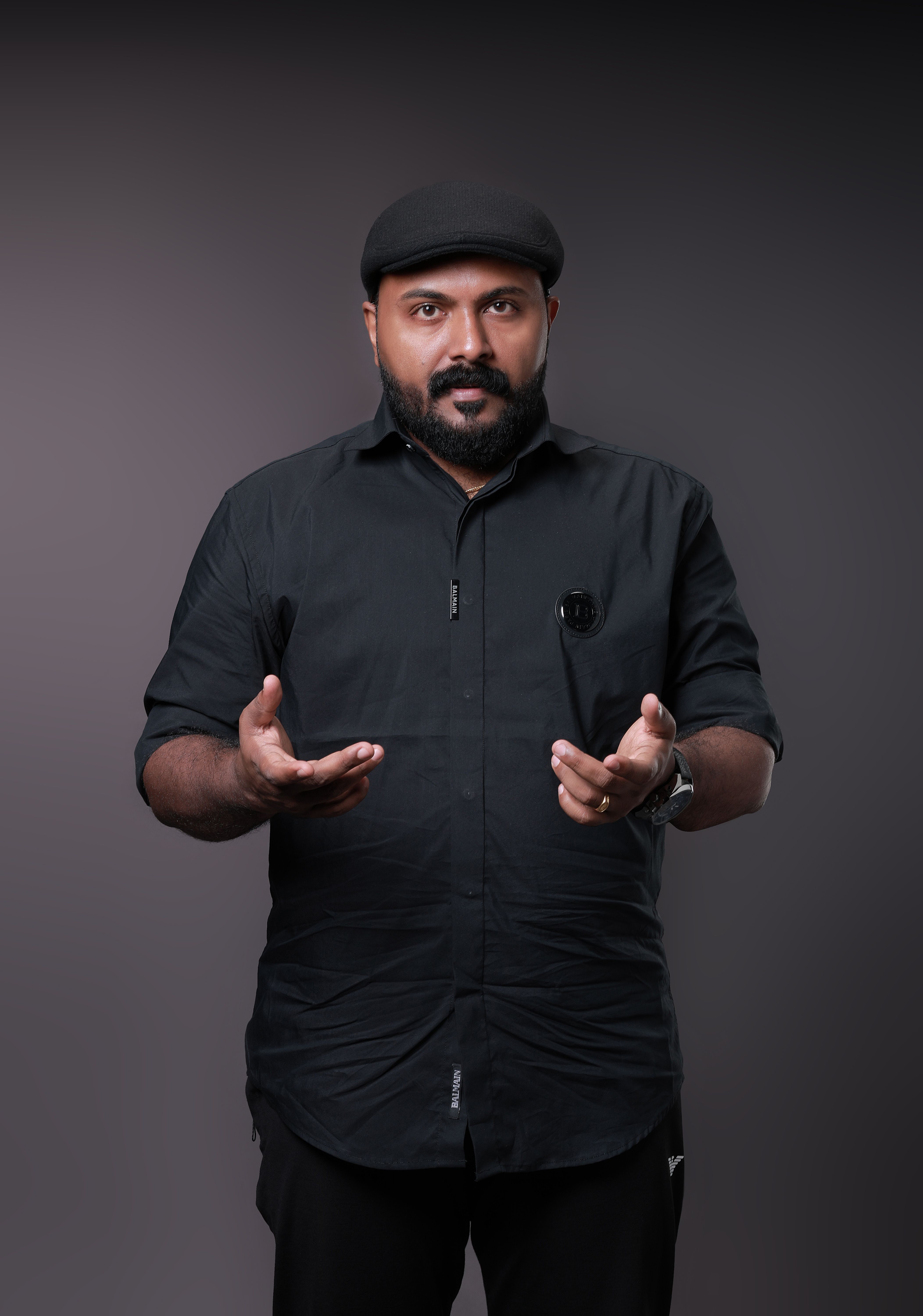 Striking studio portrait of a man with a beard and cap against a dark background.