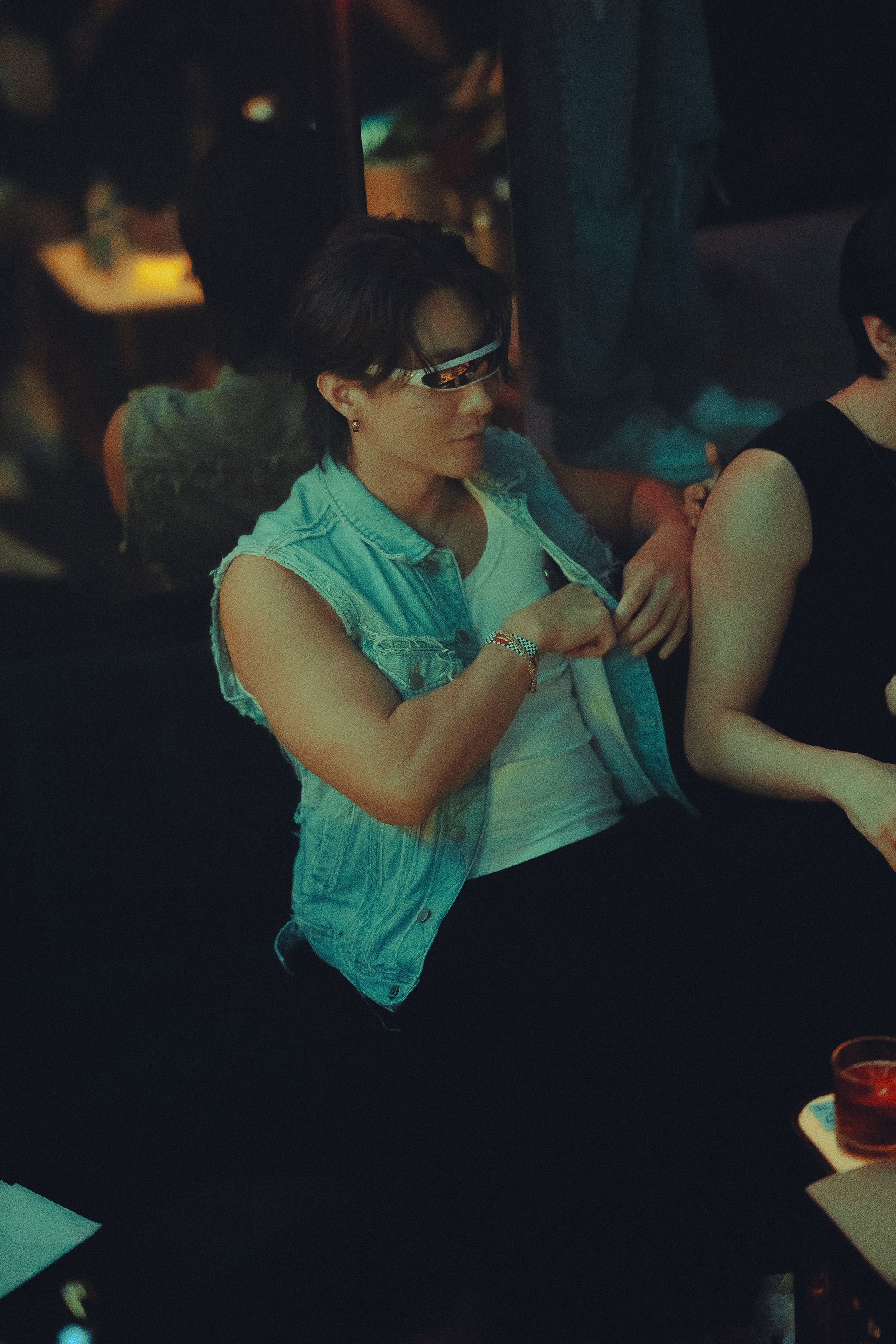 A person wearing futuristic glasses enjoys nightlife in a club, showcasing vibrant energy and style.