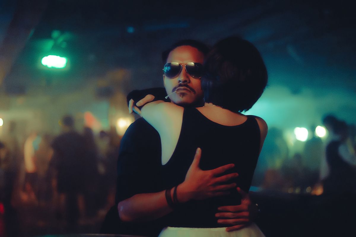 Pareja bailando en un club con iluminación cálida y ambiente íntimo