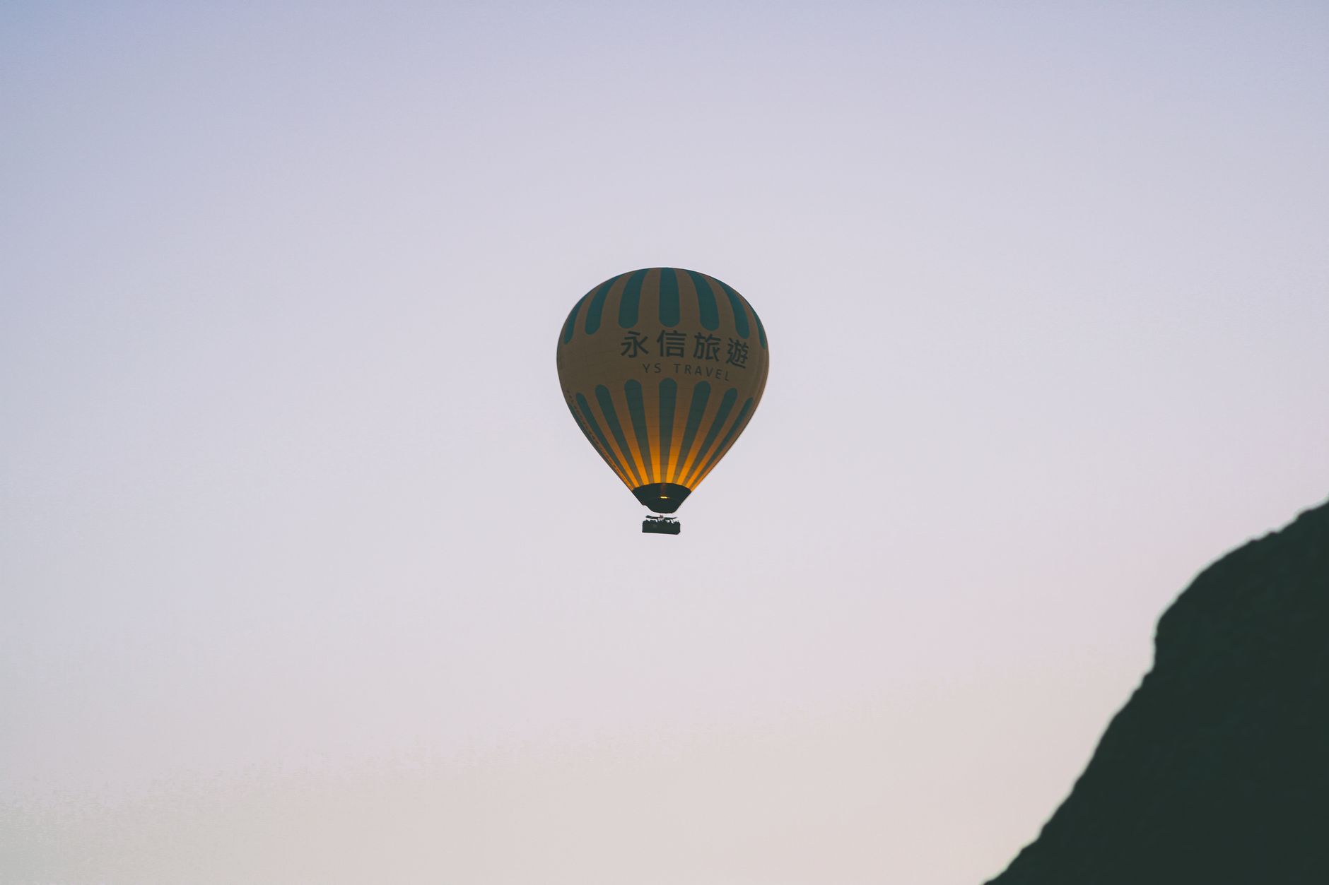 A serene hot air balloon flight against a twilight sky with mountainous silhouette.