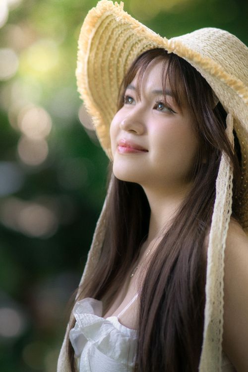 Free Portrait of a smiling woman with long hair wearing a straw hat outdoors. Stock Photo