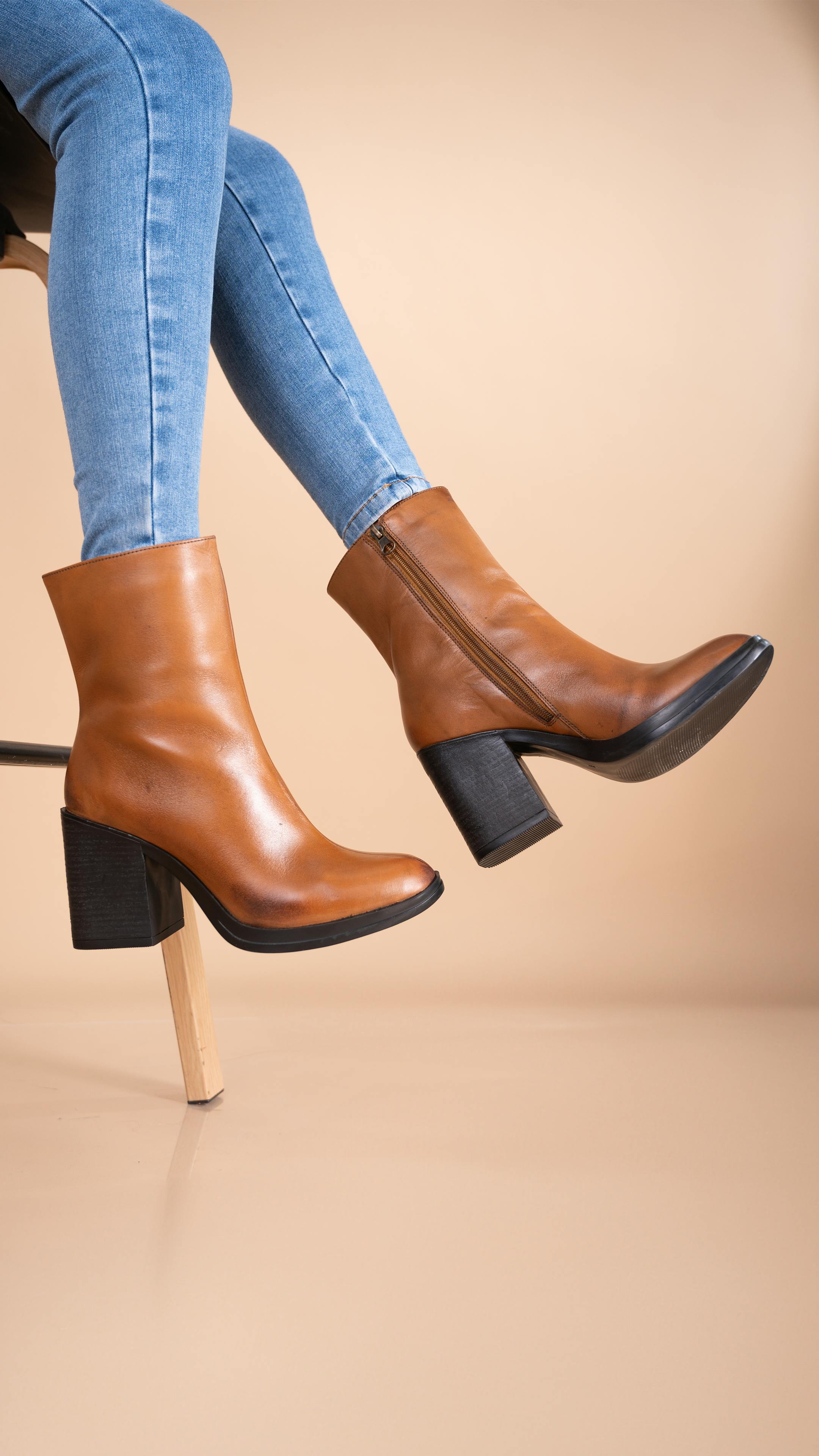 Free Brown leather boots paired with blue jeans in a stylish studio setup. Stock Photo