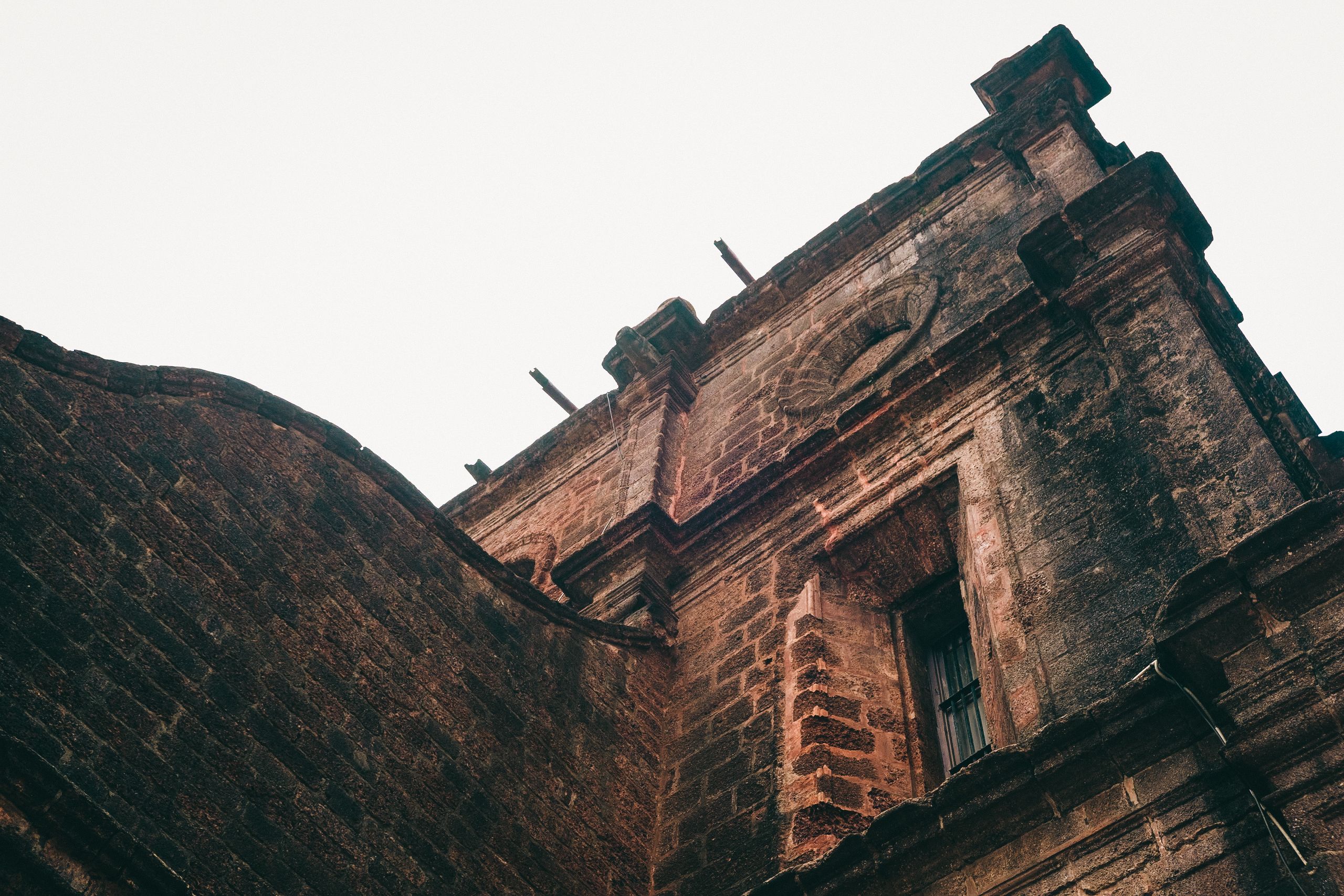 Low angle view of an old brick building in Goa showcasing historical architecture.