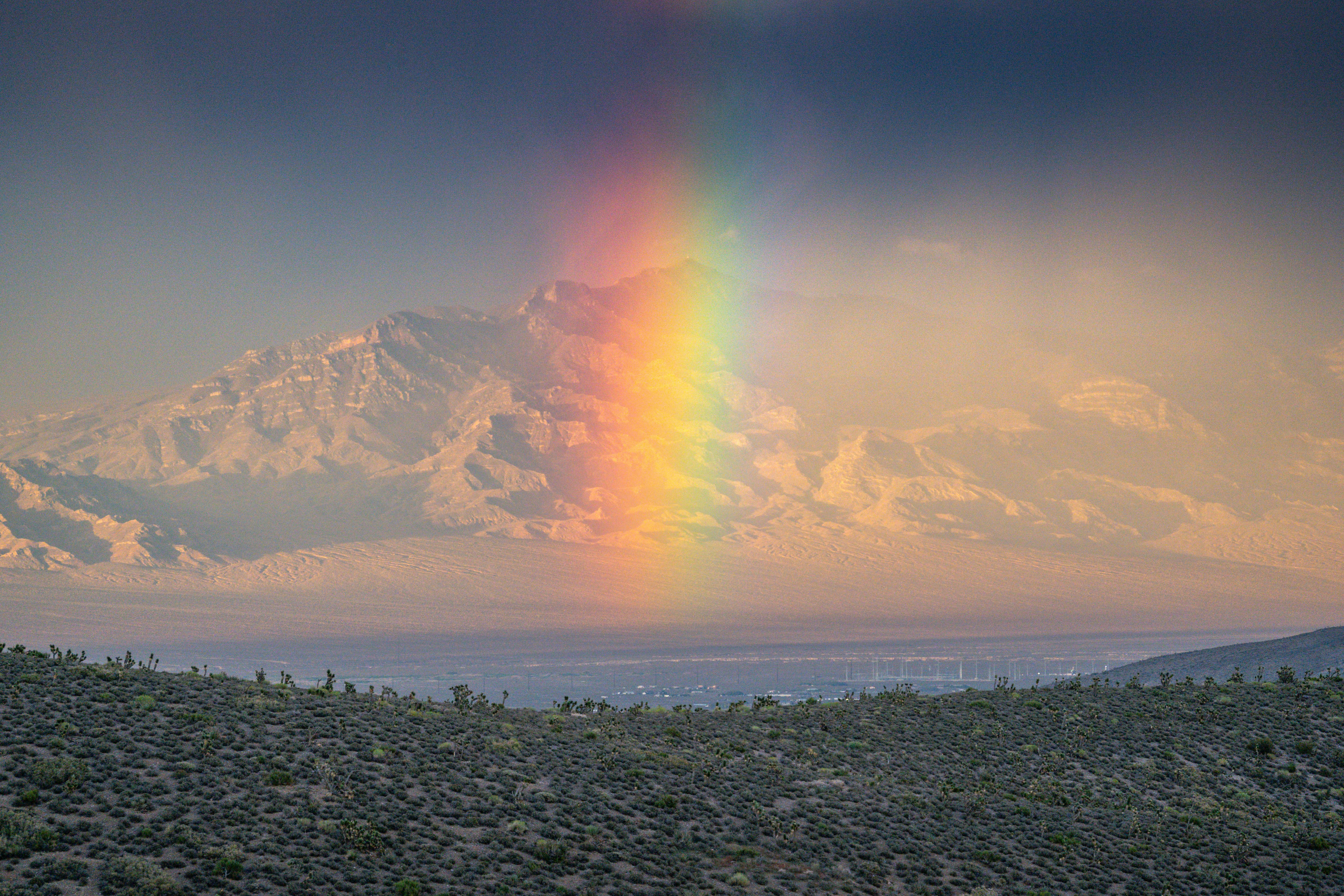 Dramatic mountain landscape featuring a vibrant rainbow over Mount Charleston, Nevada.