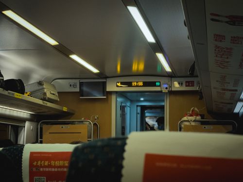 Free View of a modern train's interior with luggage racks and illuminated signs. Public transport ambiance. Stock Photo