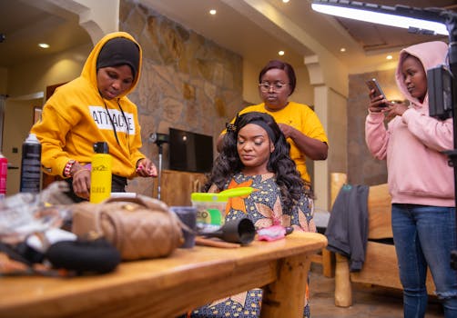 Three women collaborating on makeup and hairstyling indoors for a photoshoot.