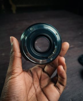 Detailed shot of a camera lens being held, ideal for photography themes.