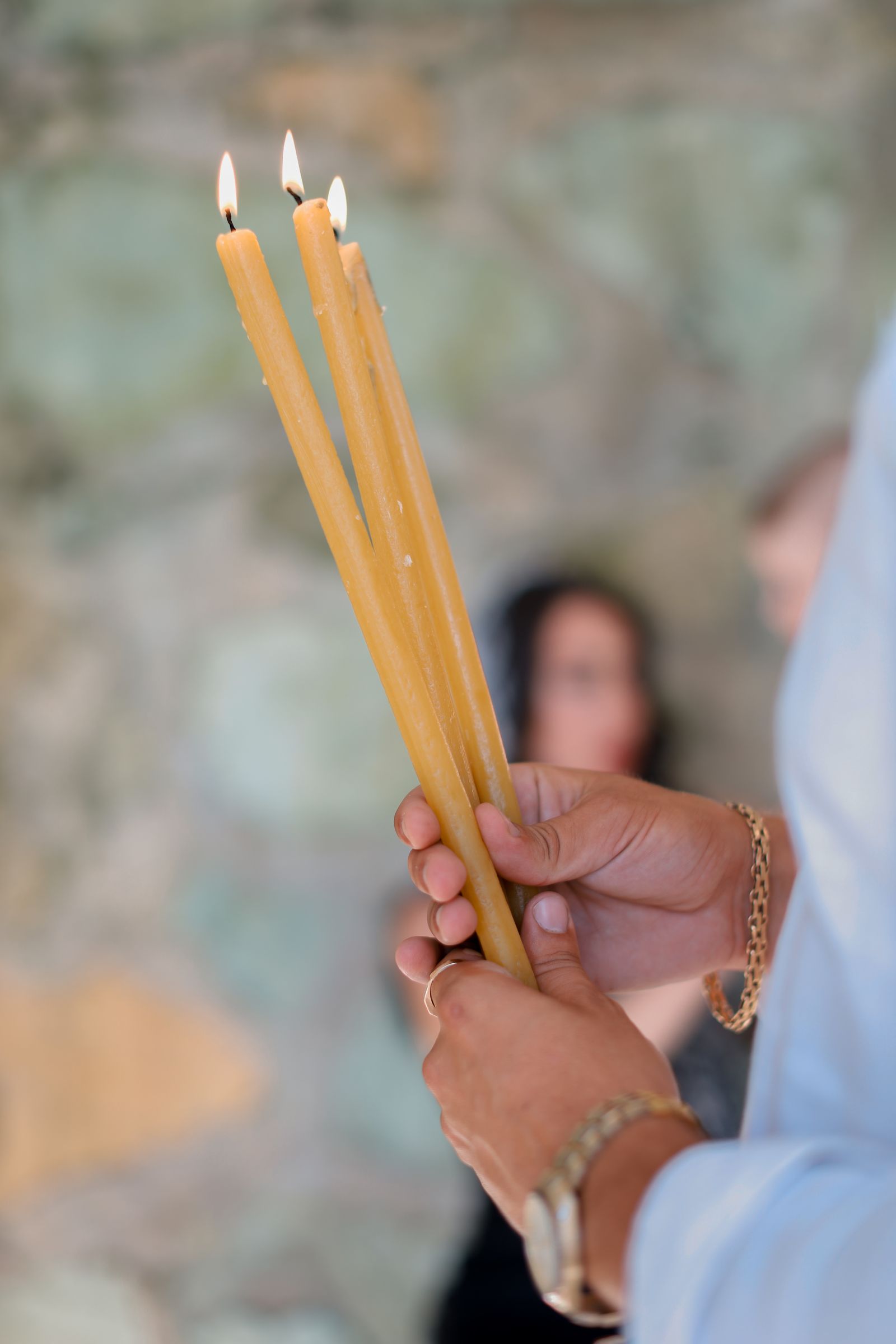Warm hands cradling lit beeswax candles in soft light