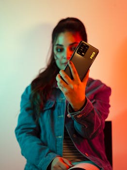 Stylish woman in denim jacket takes a selfie with smartphone indoors.