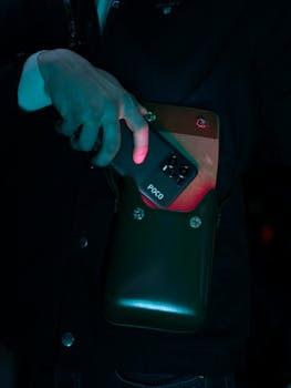 A person holds a smartphone in a bag under dramatic lighting, creating a moody atmosphere.
