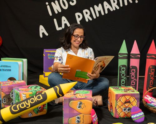 Free Joyful woman reading books in a vibrant classroom filled with colorful educational materials. Stock Photo