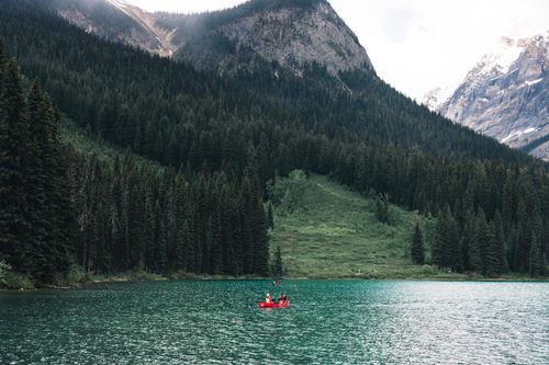 Free Scenic view of canoeing on a turquoise lake surrounded by mountains and forest in Field, BC, Canada. Stock Photo