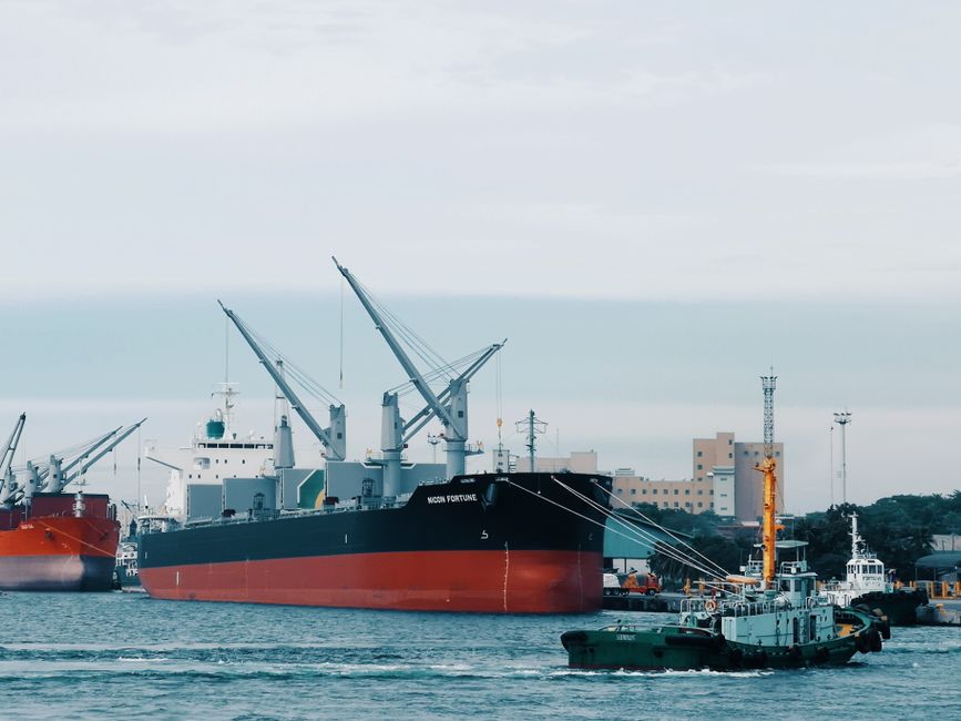 Photo by John Mark Barit View of cargo ships docked at Davao harbor with tugboat assistance in Philippines.