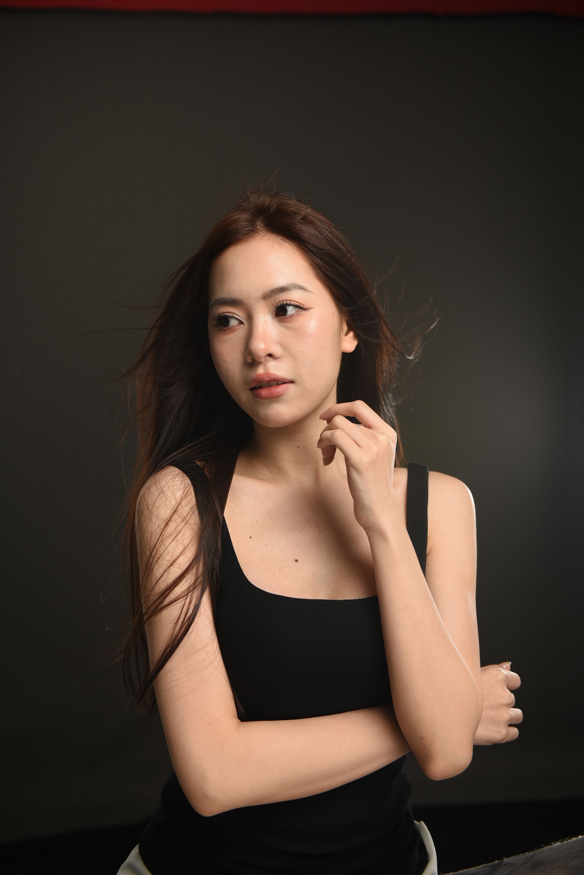 Portrait of a young woman with brunette hair in a studio, exuding elegance and grace.