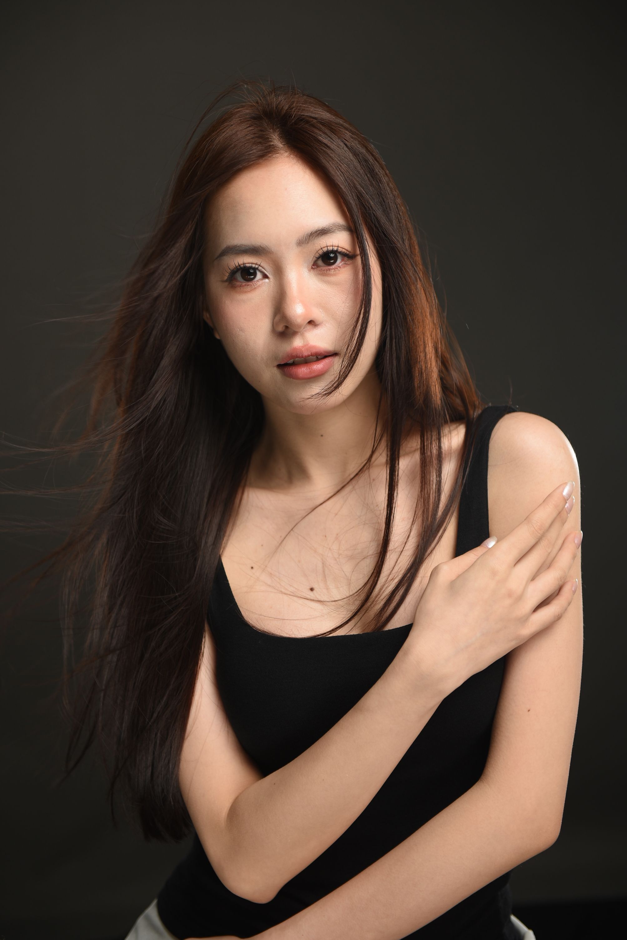 A captivating studio portrait of a woman with flowing hair in a stylish black top.