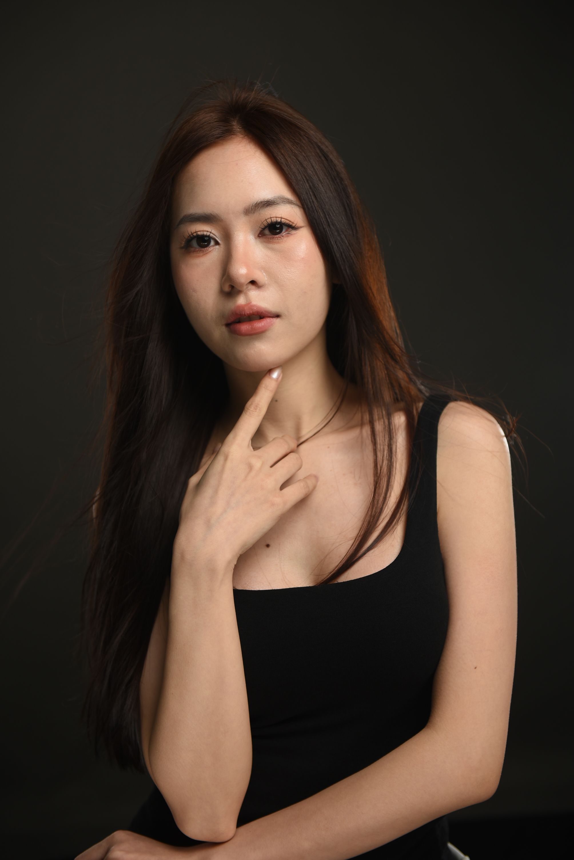 Striking studio portrait of a woman in a black top, showcasing elegance and style.