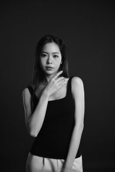 Black and white portrait of a woman in a studio setting, exuding elegance and poise.