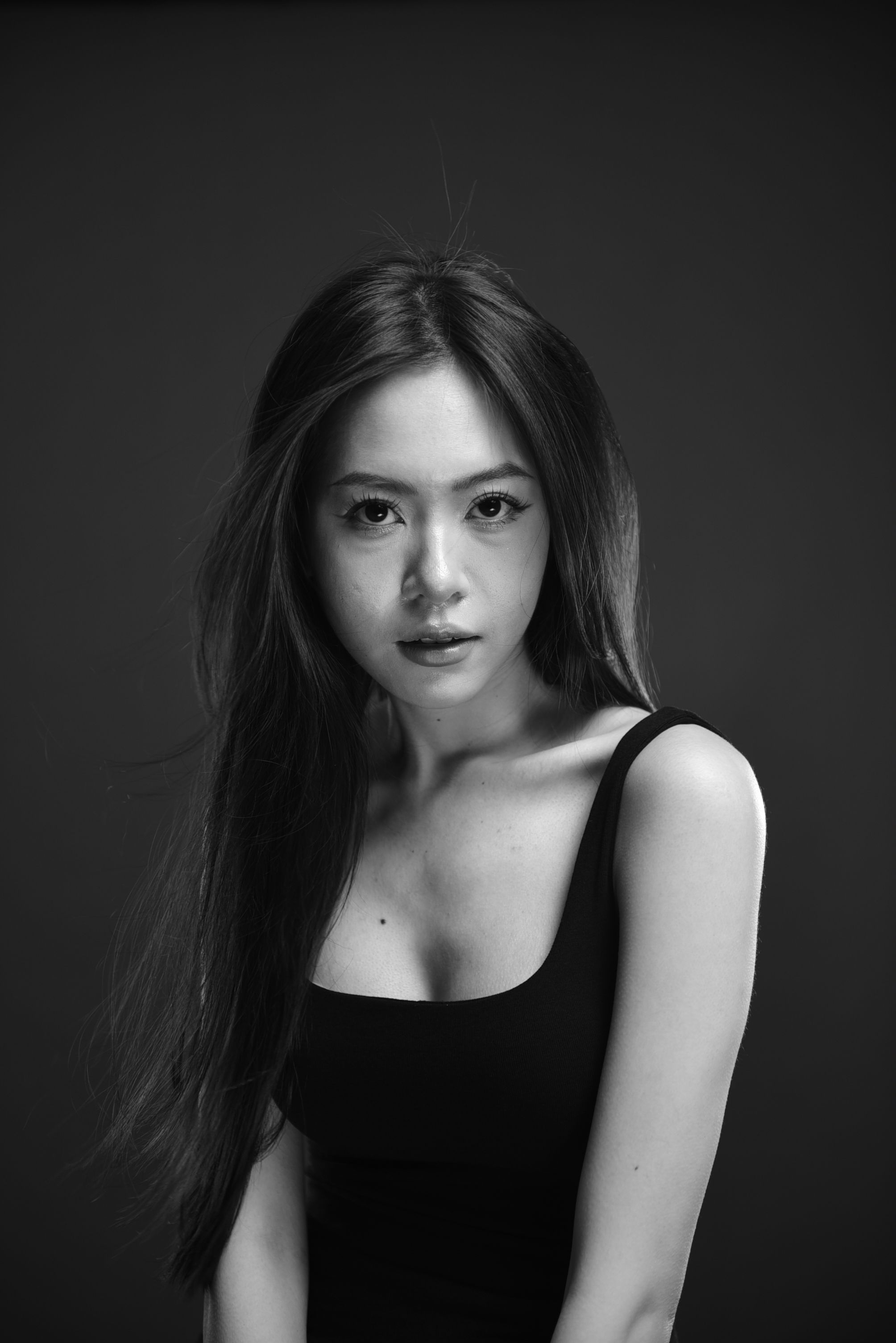 Black and white portrait of a woman with long hair in a studio setting.