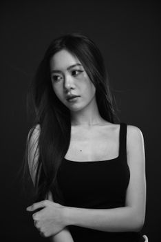 Black and white studio portrait of a woman with long hair in a tank top.