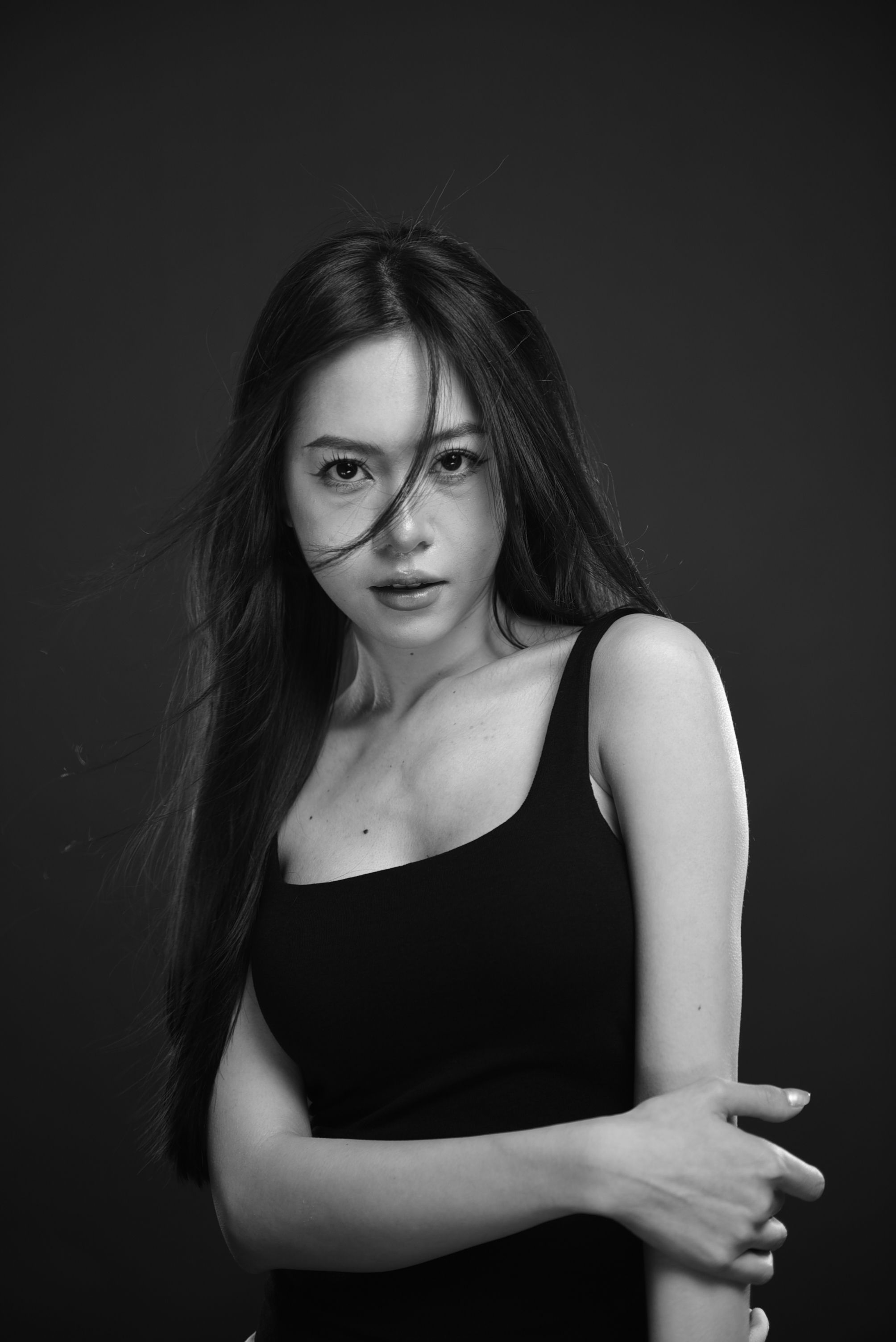 Striking black and white studio portrait of a woman with flowing hair.